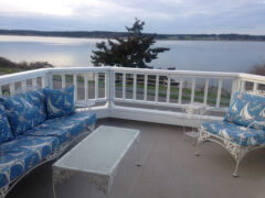 A deck couch and chair on the balcony overlooking the water